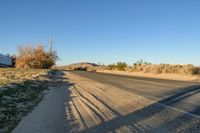 a empty street in the middle of a barren plain with dry grass growing beside it