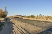 a empty street in the middle of a barren plain with dry grass growing beside it