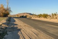 a empty street in the middle of a barren plain with dry grass growing beside it