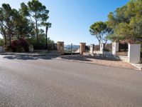 a small gate is situated in the middle of an empty road leading to a large estate