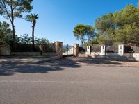 a small gate is situated in the middle of an empty road leading to a large estate