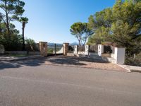 a small gate is situated in the middle of an empty road leading to a large estate