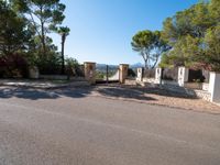 a small gate is situated in the middle of an empty road leading to a large estate