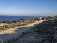 the lone and empty road goes out to the beach side from the cliff, surrounded by large grassy areas