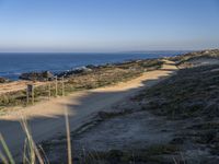 the lone and empty road goes out to the beach side from the cliff, surrounded by large grassy areas