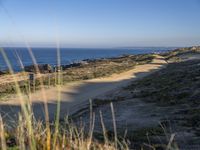 the lone and empty road goes out to the beach side from the cliff, surrounded by large grassy areas