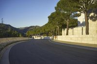 an empty road and a tall building on the side of a hill with trees in the middle