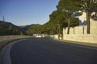 an empty road and a tall building on the side of a hill with trees in the middle