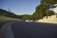 an empty road and a tall building on the side of a hill with trees in the middle