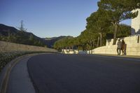 an empty road and a tall building on the side of a hill with trees in the middle