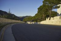 an empty road and a tall building on the side of a hill with trees in the middle