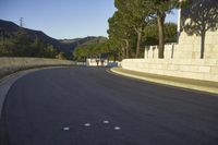 an empty road and a tall building on the side of a hill with trees in the middle