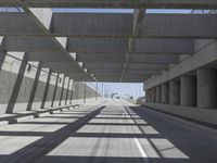 an empty road lined with cement structures and cement pillars, along with multiple ramps below