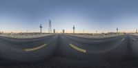 a fish eye lens view of an empty road at sunrisetime, with multiple lines in the middle of the road