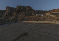 the road is empty in front of a huge rock wall with a few stairs on it