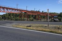 the empty road is next to an open bridge with a red color structure on it