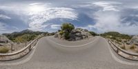 a view of an empty road and a sky background with clouds above it as seen from a fish eye lens