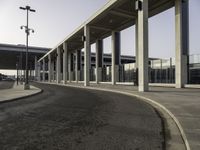 an empty road leading to a large open area with lots of columns and benches nearby