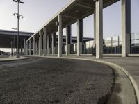 an empty road leading to a large open area with lots of columns and benches nearby