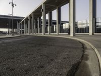 an empty road leading to a large open area with lots of columns and benches nearby