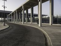 an empty road leading to a large open area with lots of columns and benches nearby