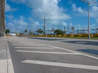 a empty empty road on a bright blue day with a view of a marina in the distance