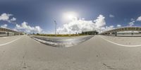 this fish eye is full view of an empty road and a large building in the background