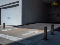 an empty street with a building in the background and some white arrows painted on the floor