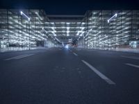 an empty road in a modern city at night with buildings and lamps on both sides