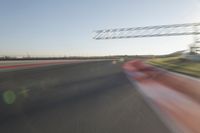 a car drives down an empty track in the sun with motion blurry from the tracks