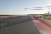 a car drives down an empty track in the sun with motion blurry from the tracks