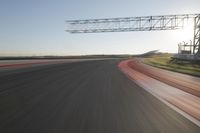 a car drives down an empty track in the sun with motion blurry from the tracks