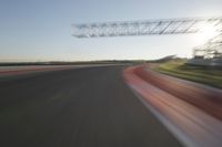 a car drives down an empty track in the sun with motion blurry from the tracks