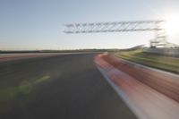 a car drives down an empty track in the sun with motion blurry from the tracks