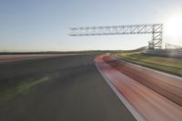 a car drives down an empty track in the sun with motion blurry from the tracks