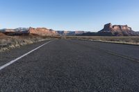 an empty empty road with mountains in the background and a sky with no clouds behind