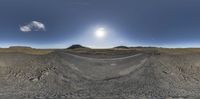 an upside down view of the road in an empty mountain landscape with a sun rising over the top