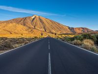 the road to el teide is empty on the desert land, with mountains in the background