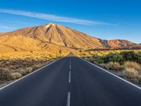 the road to el teide is empty on the desert land, with mountains in the background