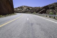 there is a picture of the empty road through the mountain range in the desert to the left, and right the yellow stripe in the foreground in the middle is a white on the road