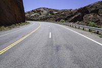 there is a picture of the empty road through the mountain range in the desert to the left, and right the yellow stripe in the foreground in the middle is a white on the road