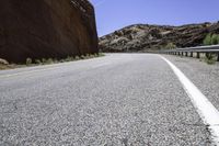 there is a picture of the empty road through the mountain range in the desert to the left, and right the yellow stripe in the foreground in the middle is a white on the road