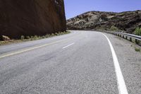 there is a picture of the empty road through the mountain range in the desert to the left, and right the yellow stripe in the foreground in the middle is a white on the road