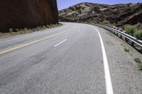 there is a picture of the empty road through the mountain range in the desert to the left, and right the yellow stripe in the foreground in the middle is a white on the road