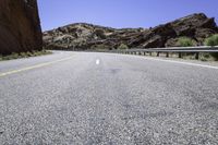 there is a picture of the empty road through the mountain range in the desert to the left, and right the yellow stripe in the foreground in the middle is a white on the road