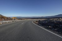 there is a long empty road leading to the mountain range where the traffic signals can be seen