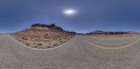 an empty road stretches into the sky near a mountain range and the sun shines on the horizon