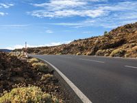 an empty road through the mountains in a desert scene is pictured on a clear day