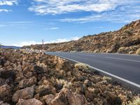 an empty road through the mountains in a desert scene is pictured on a clear day