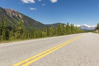 an empty road with mountains and pine trees in the background, in canada - stock image